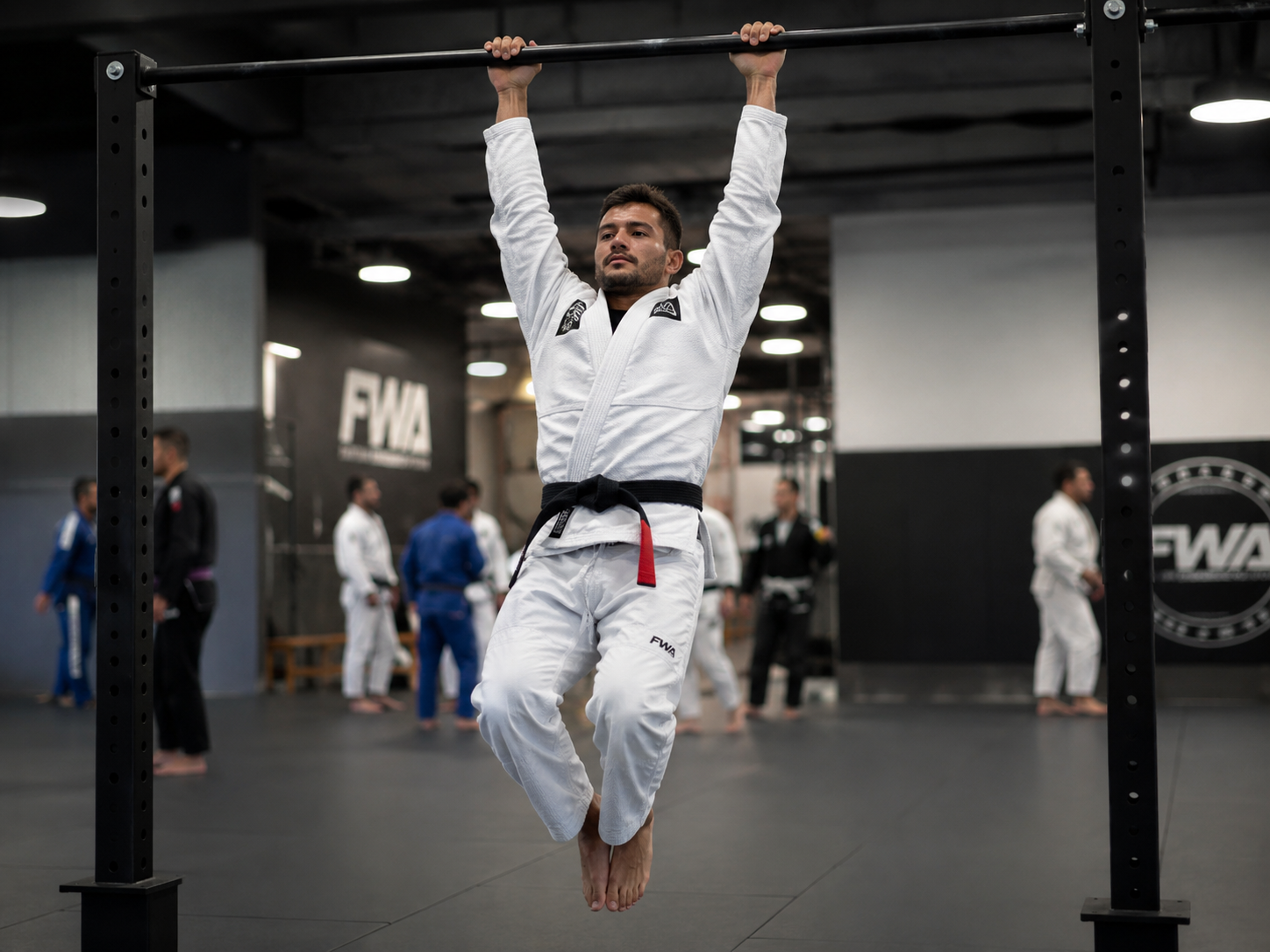 Pratiquant de JJB réalisant un exercice de renforcement du grip en suspension à une barre de traction
