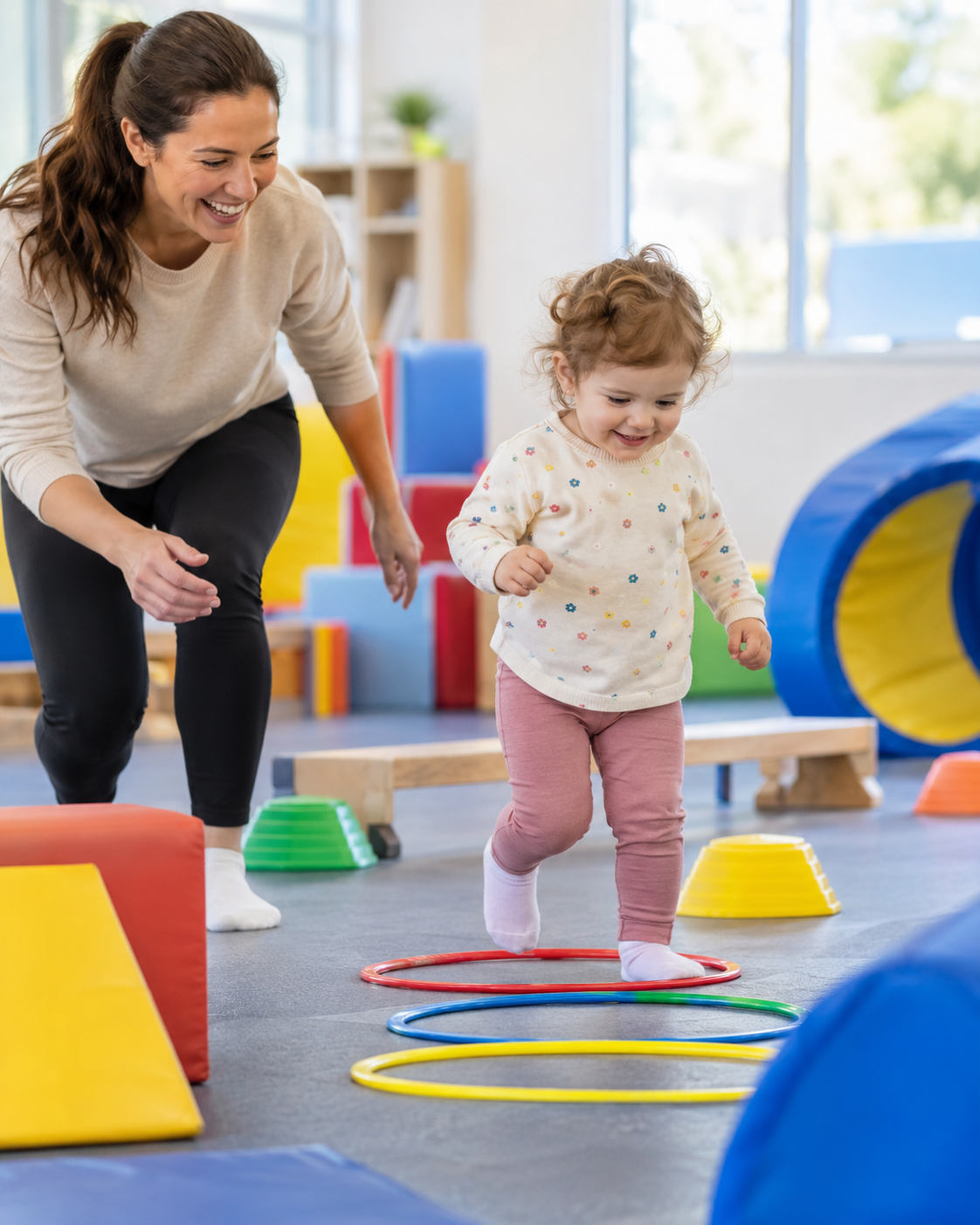 Parent et enfant de 2 ans sur un parcours de motricité avec cerceaux et modules en mousse